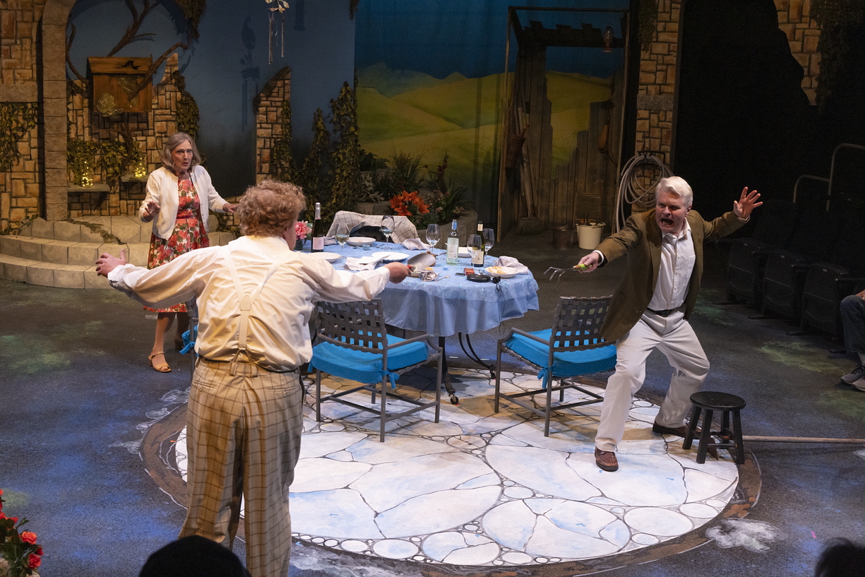 Ward threatening another actor in a garden with a 3-pronged hand cultivatprr